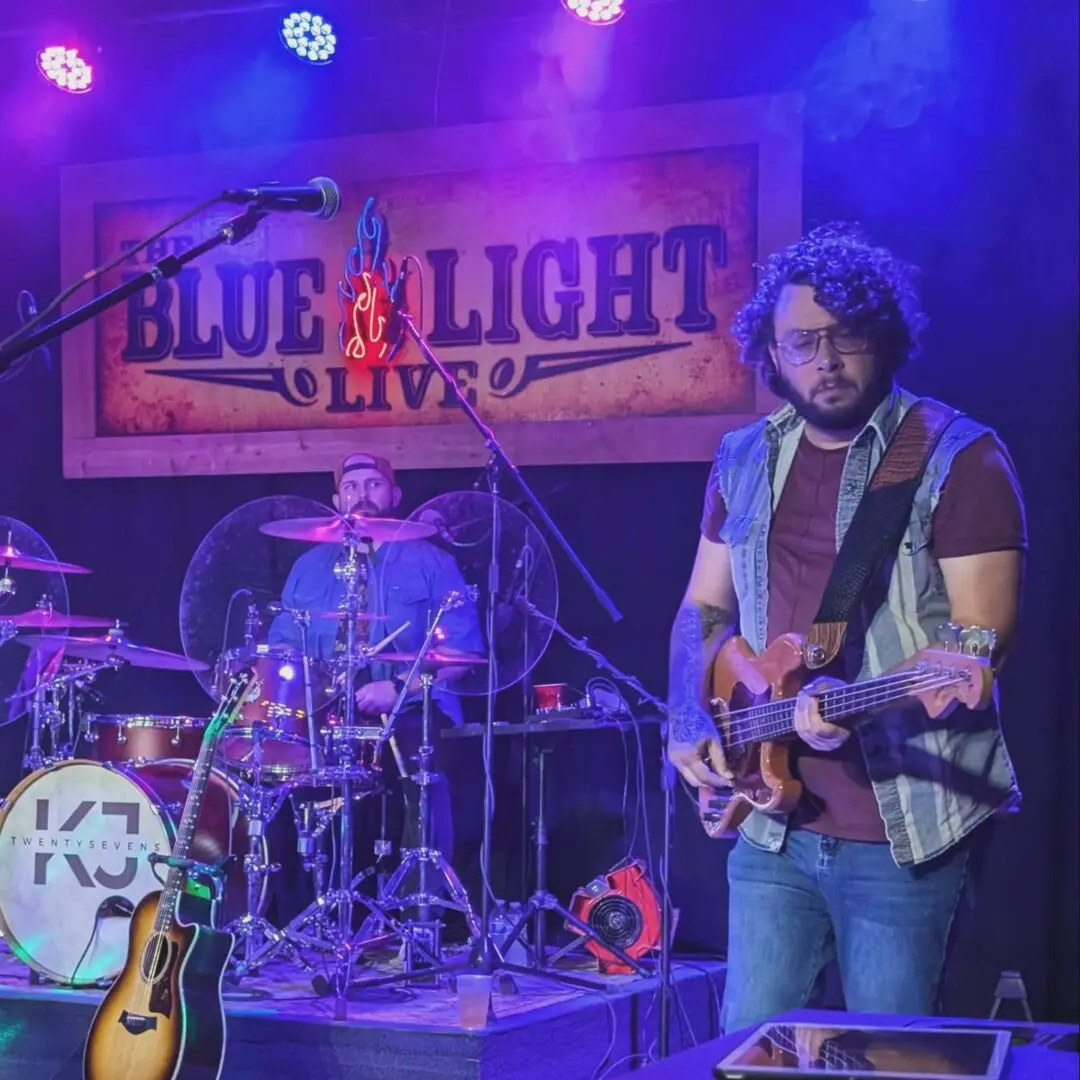 A man playing guitar on stage with other people.